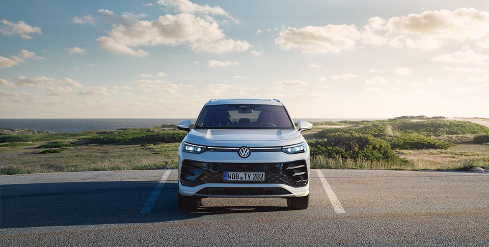 ein wei&szlig;er VW steht in Frontansicht auf einem Parkplatz in der Natur